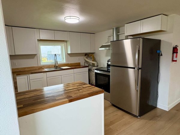 Kitchen with butcher-block counters, white cabinets and a stainless refrigerator