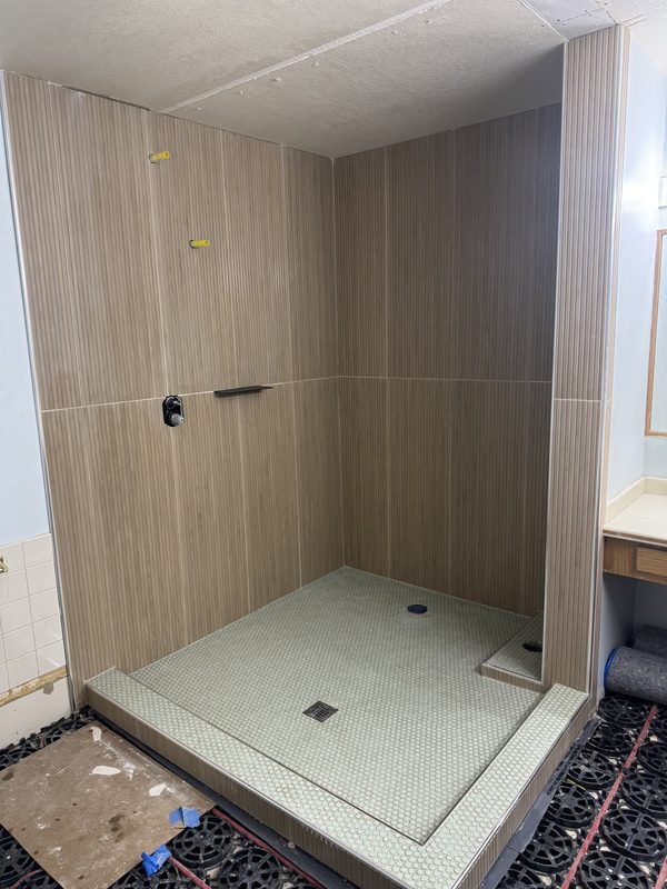 Walk-in shower with tall wood-look wall tile and a penny-tile floor