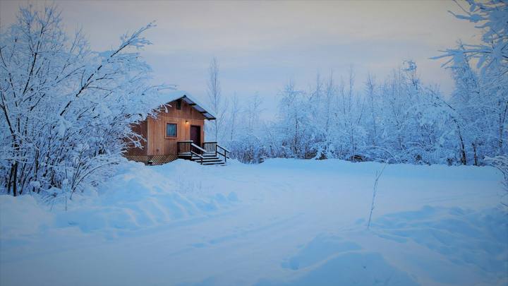Small wooden cabin surrounded by deep snow