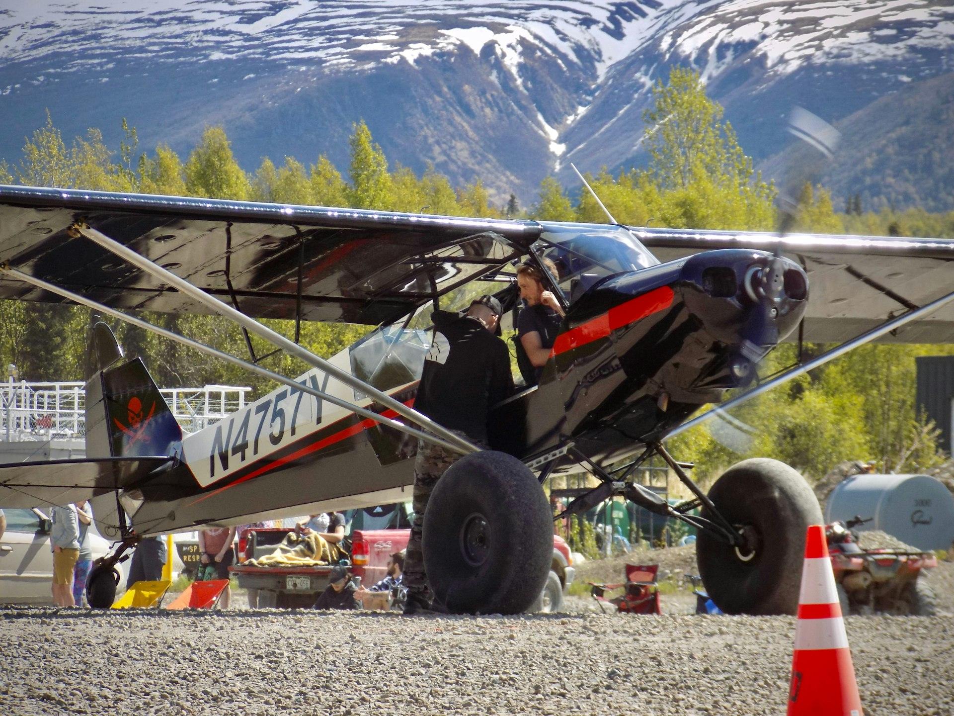 Bush plane with tundra tires parked beneath Alaska mountains